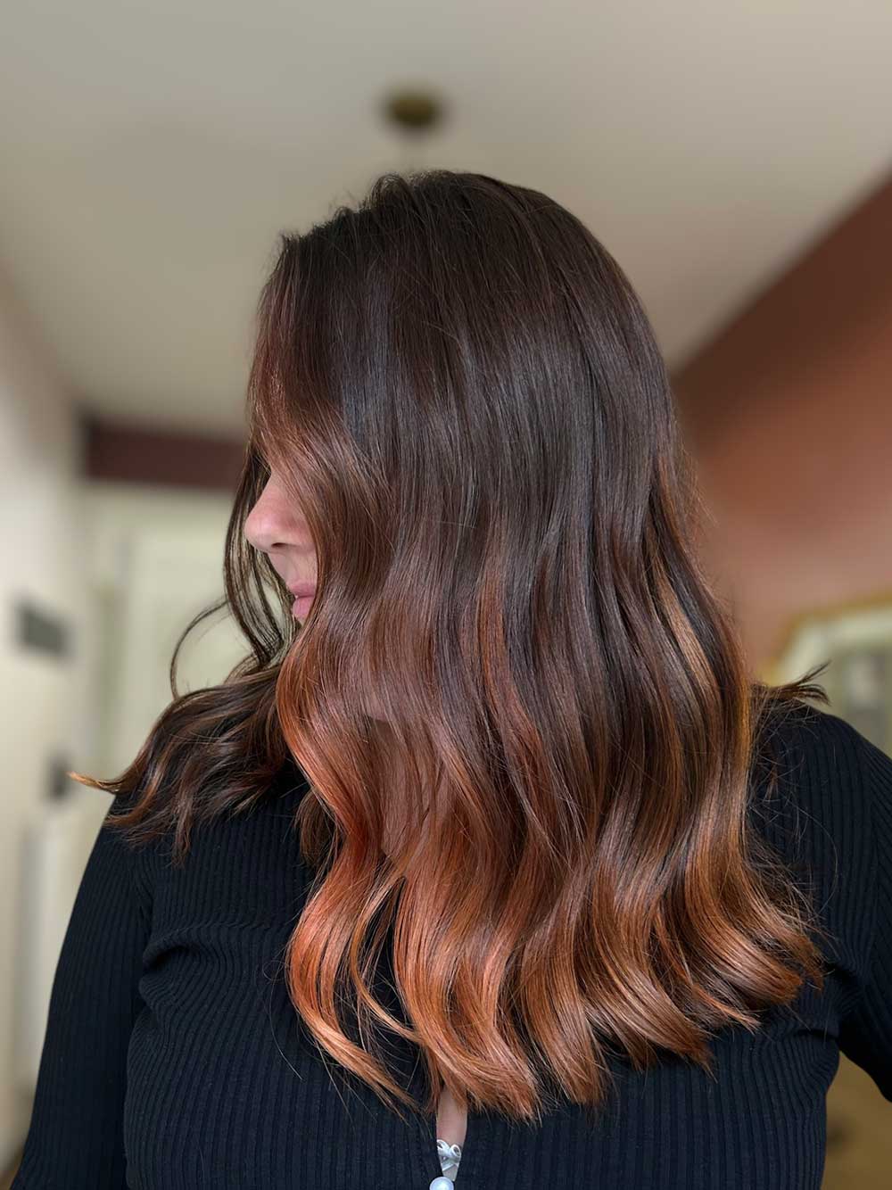 Une femme qui montre ses cheveux avec une coloration type balayage réalisée par le coiffeur à Bordeaux Dissemblance