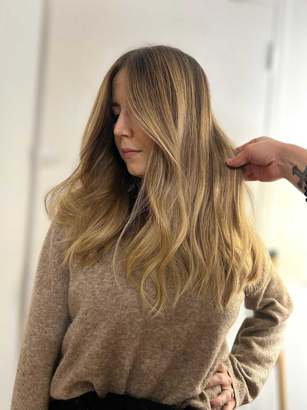 Une femme qui montre ses cheveux avec une coloration type balayage réalisée par le coiffeur à Bordeaux Dissemblance