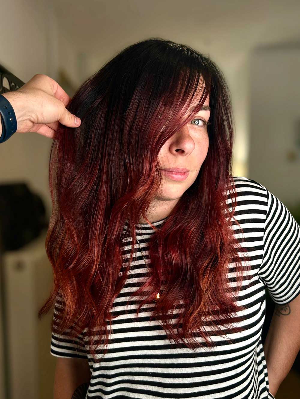Une femme, avec un tee-shirt à rayures, qui montre sa coupe de cheveux avec une coloration réalisée par le coiffeur à Bordeaux Dissemblance
