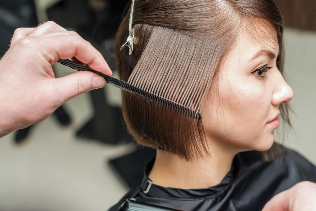 une femme de profil se fait couper les cheveux