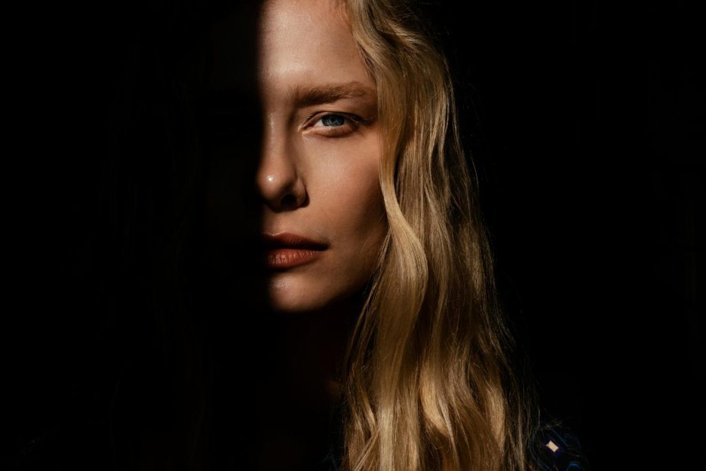 Visage de femme blonde qui sort de l'ombre : balayage ou mèches blondes ?